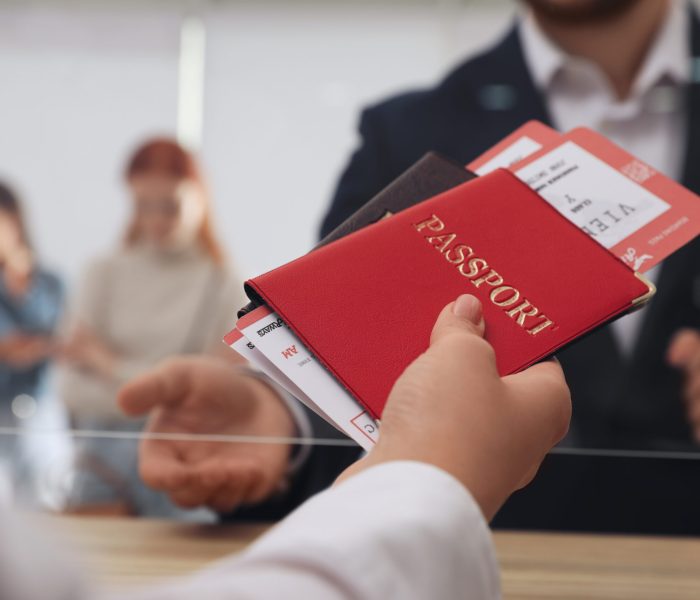 Agent giving passports with tickets to client at check-in desk in airport, closeup